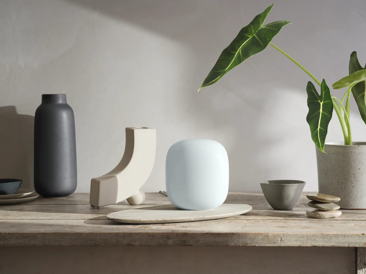 Nest Wifi Pro is sitting on a table next to plants and decor