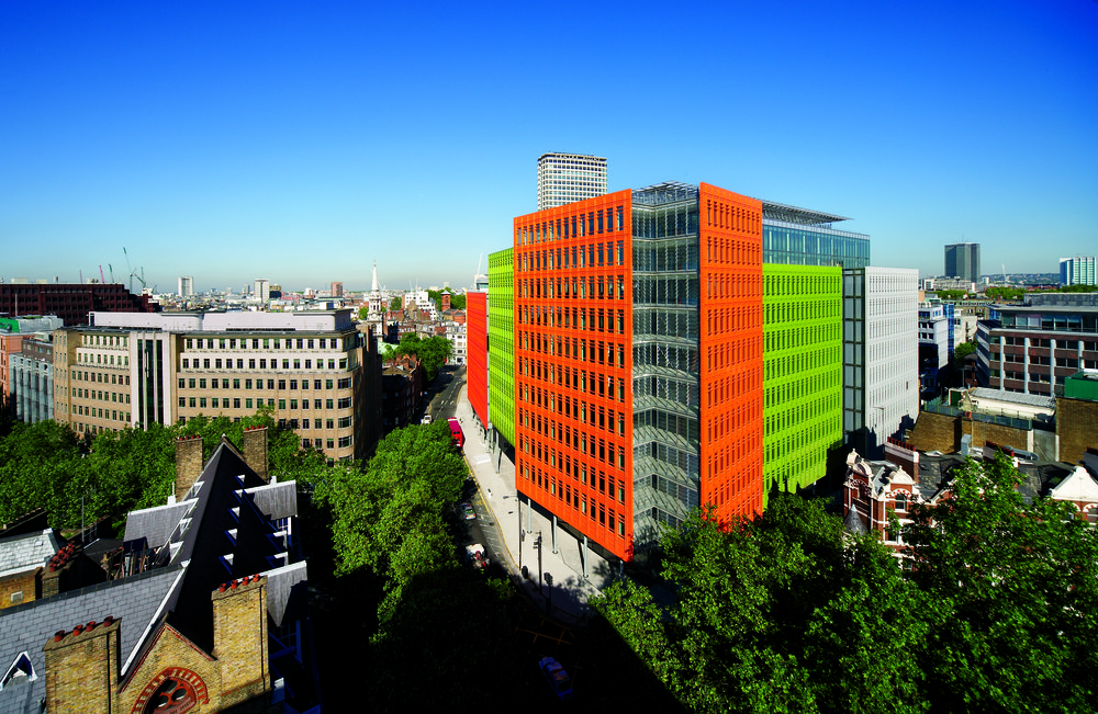 The brightly colored Central St Giles building (orange, green, grey and white) stands tall against a bright blue background of the Central London skyline