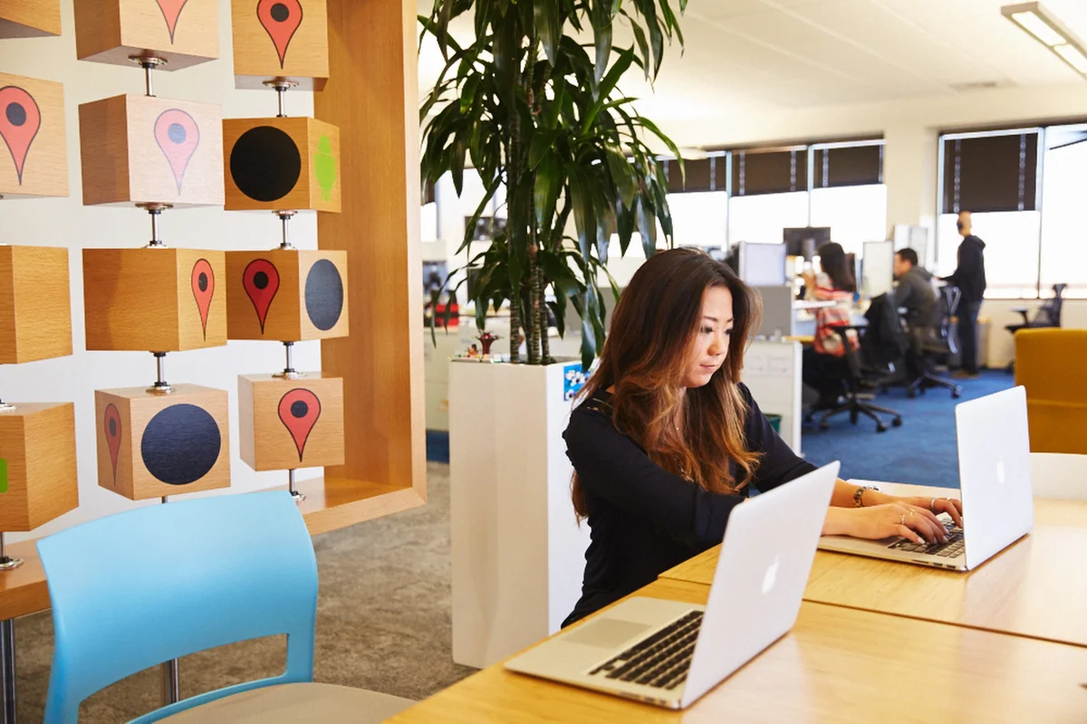 Two women sitting on a beanbag, working in an office