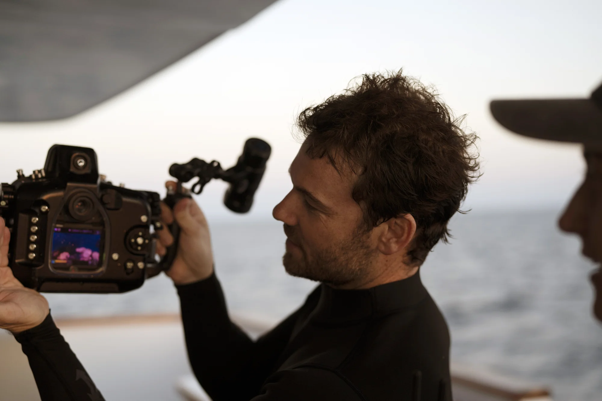 Johnny in his wetsuit holds up the camera showing a picture he took of the underwater coral.