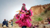 Eine malische Tänzerin tritt bei einer Zeremonie auf und trägt ein farbenfrohes Kostüm und eine Maske.