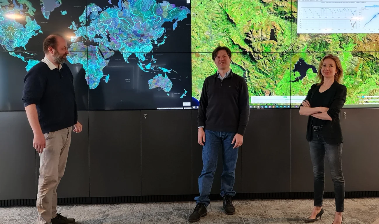 Three people standing in front of a digital map.