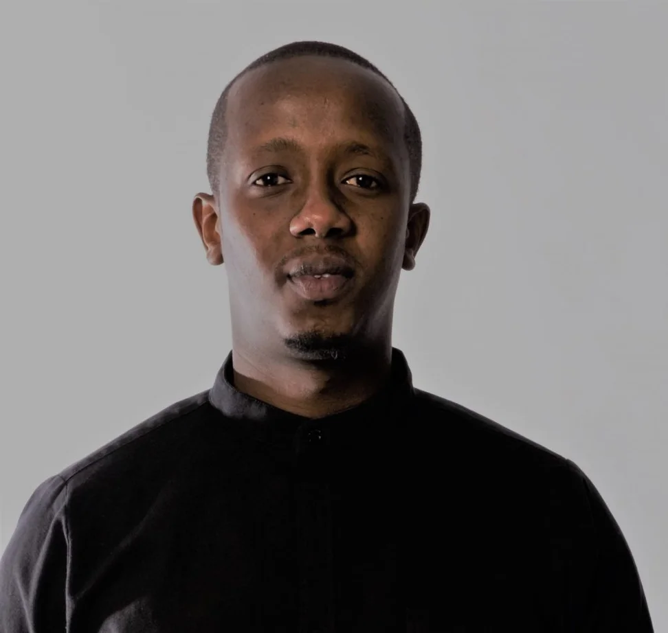 A man wearing a black shirt smiles at the camera.