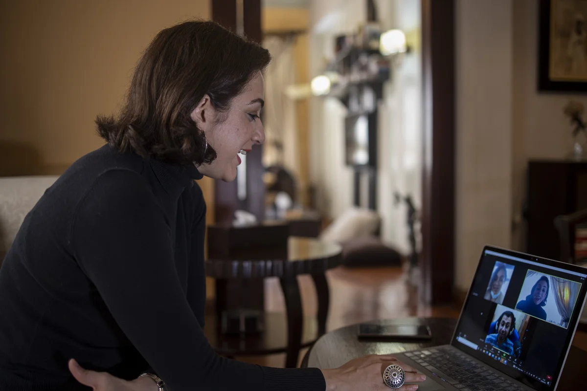 Dina Aboughazala holding a virtual meeting with other members of the team online connected via the laptop in front of her.