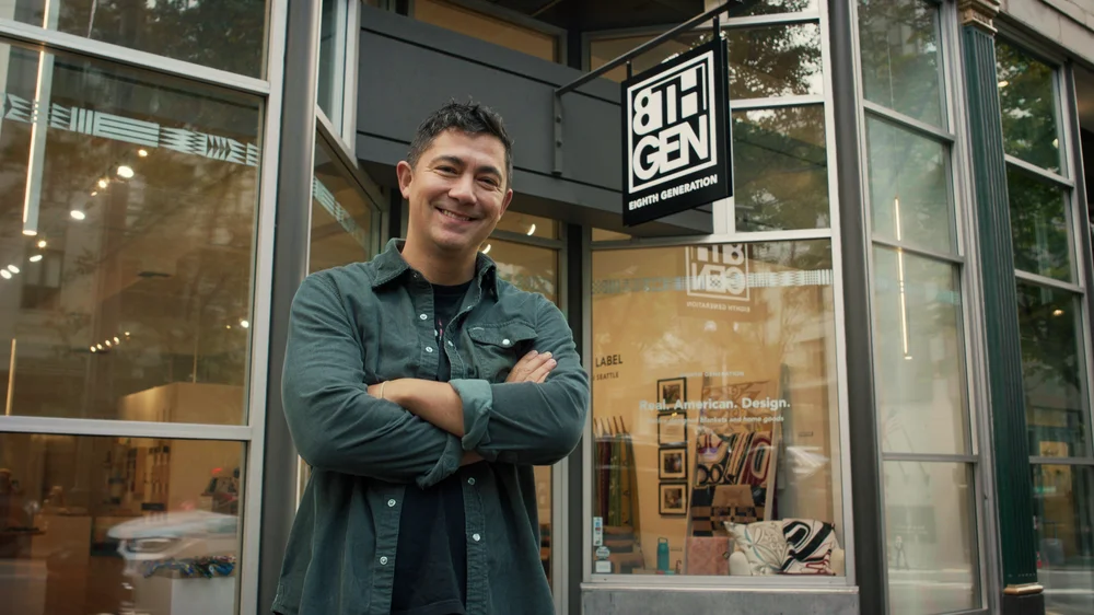 Nooksack member, Louie Gong, who founded the lifestyle brand Eighth Generation in part to create more opportunities for Indigenous artists, stands in front of the brick and mortar storefront of the business.