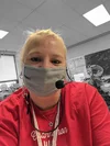 Renee sits at her desk with a mask teaching her students.