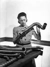 Black & white photo of Elsie MacGill holding and  inspecting a metal tube.