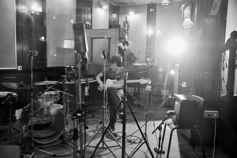 Black and white photograph of a musician from the band Corte Real with his guitar in the recording studio