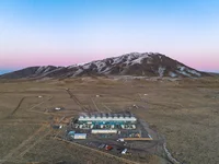 Aerial image of the geothermal plant set against mountains and a colorful sky.