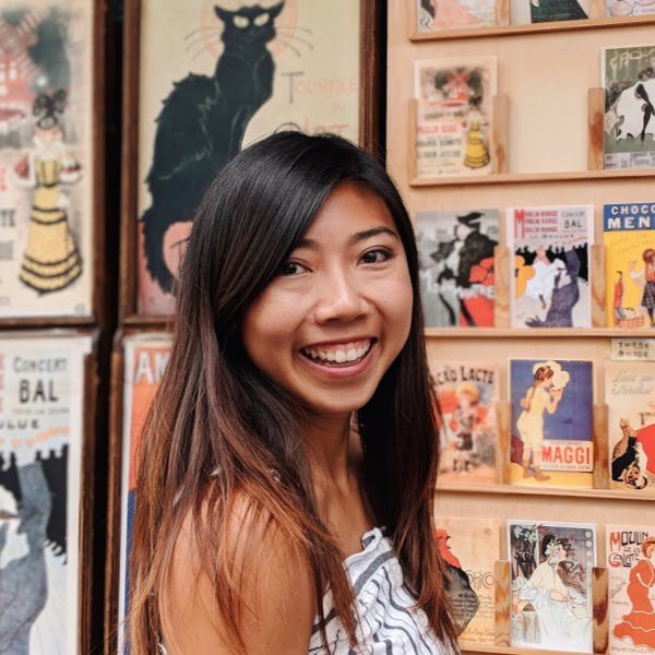 Woman with long hair smiling in front of a gallery wall.