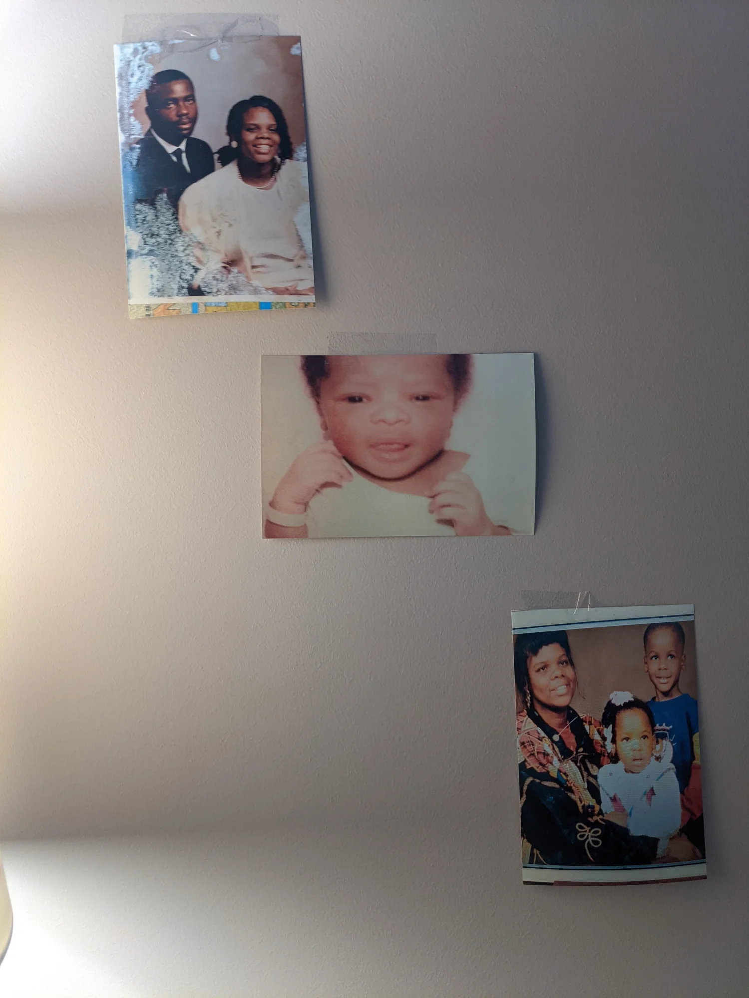 Foto von einer Wand , an der drei Familienfotos hängen.