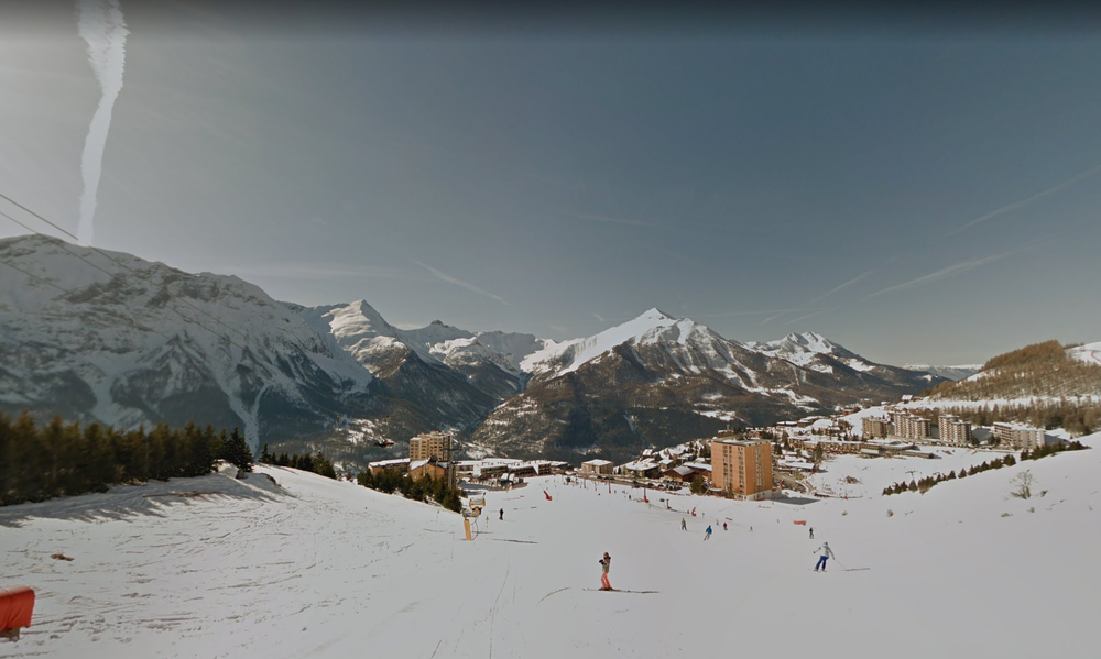 Image showing skiers skiing down a mountain surrounded by snowy peaks.