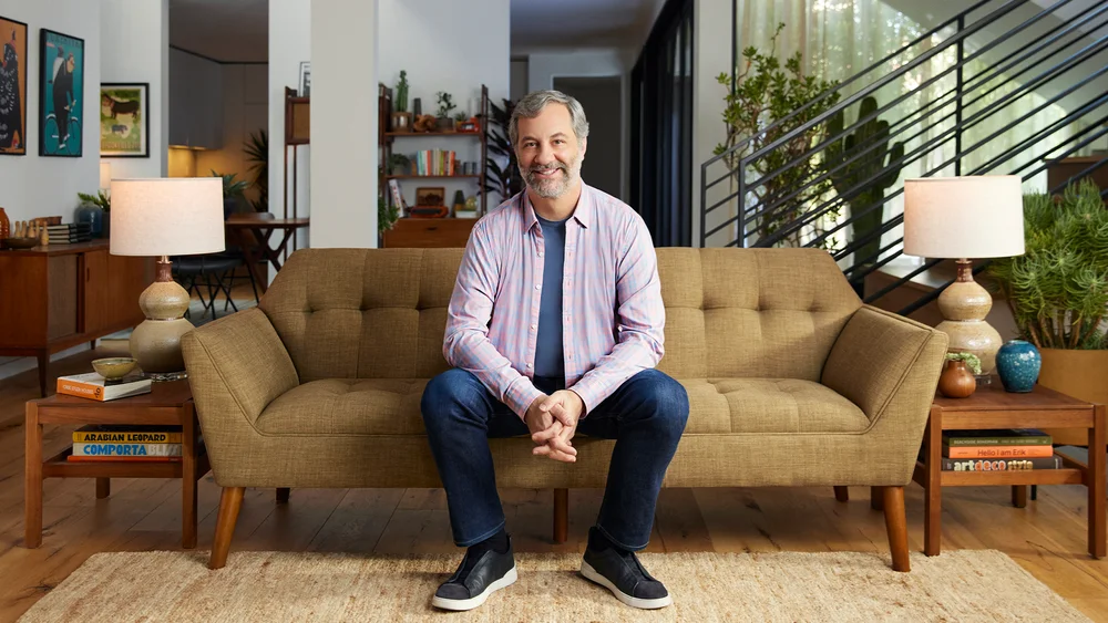 Judd Aptatow sits on a couch and looks at the camera