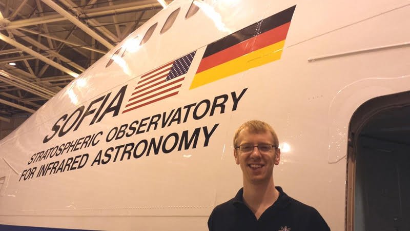 Garrett standing in front of a modified Boeing 747SP airplane with the words “Sofia Stratospheric Observatory For Infrared Astronomy” along with an American and German flag.