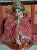 A homemade miniature figure of Goddess Lakshmi wrapped in a red saree with golden embellishments