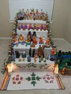 A five-step staircase like structure displaying an array of festive dolls decorated with lamps, artistic designs and flowers