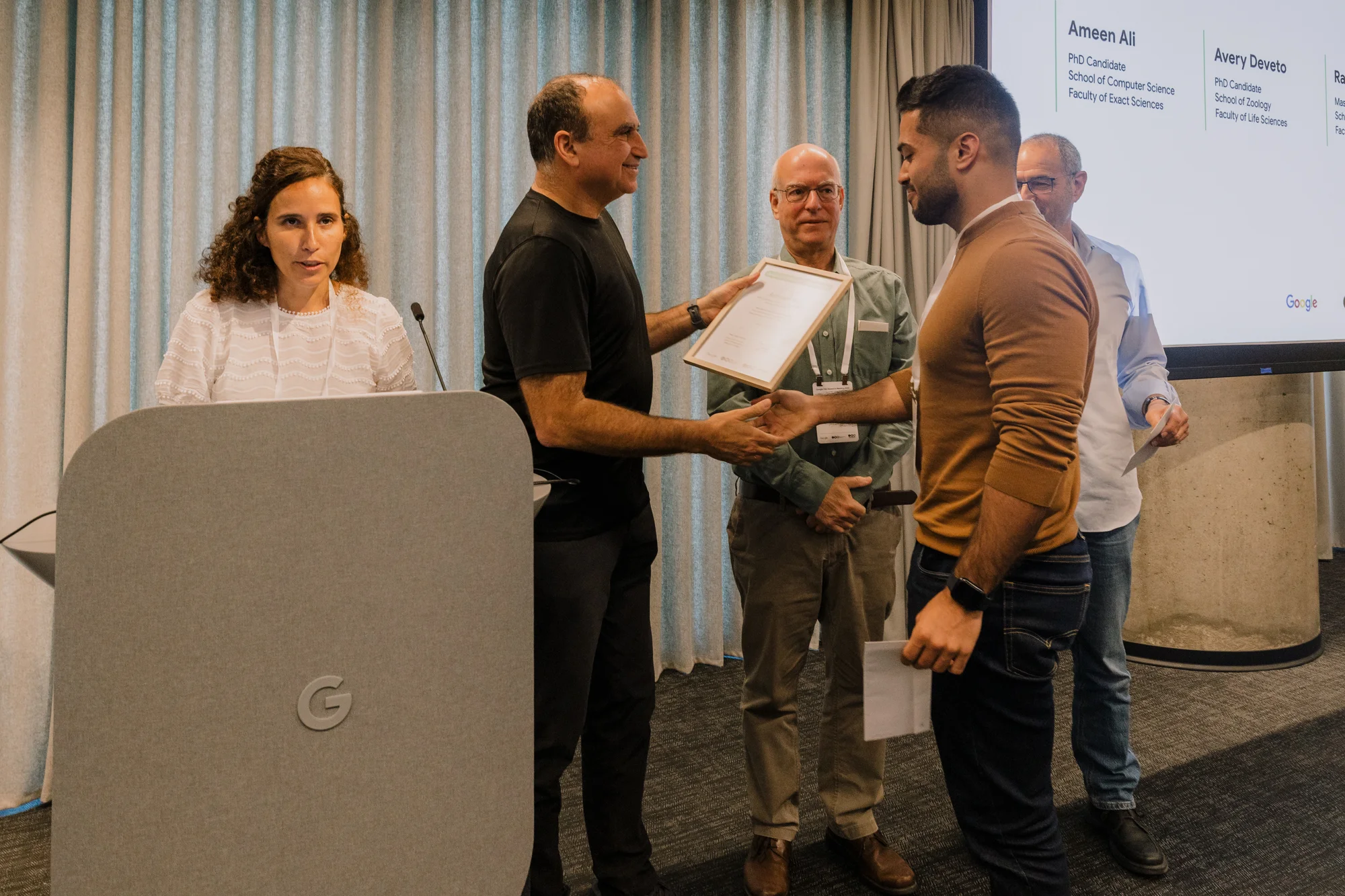One person speaking behind a podium; one person handing a certificate to another person, while two people stand next to them smiling