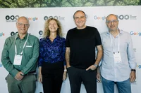 Four people standing in front of a picture wall looking at the camera and smiling