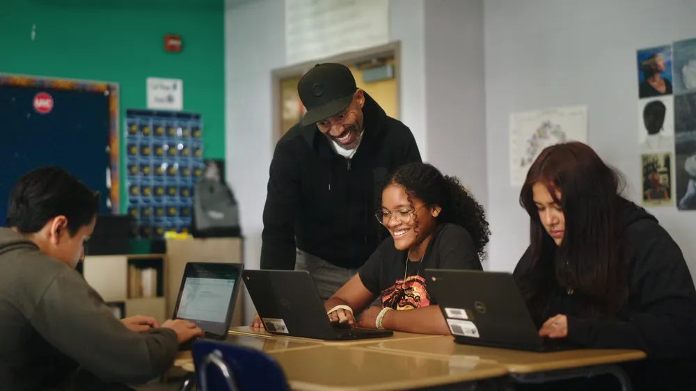 Students sitting at a table in a classroom with their teacher