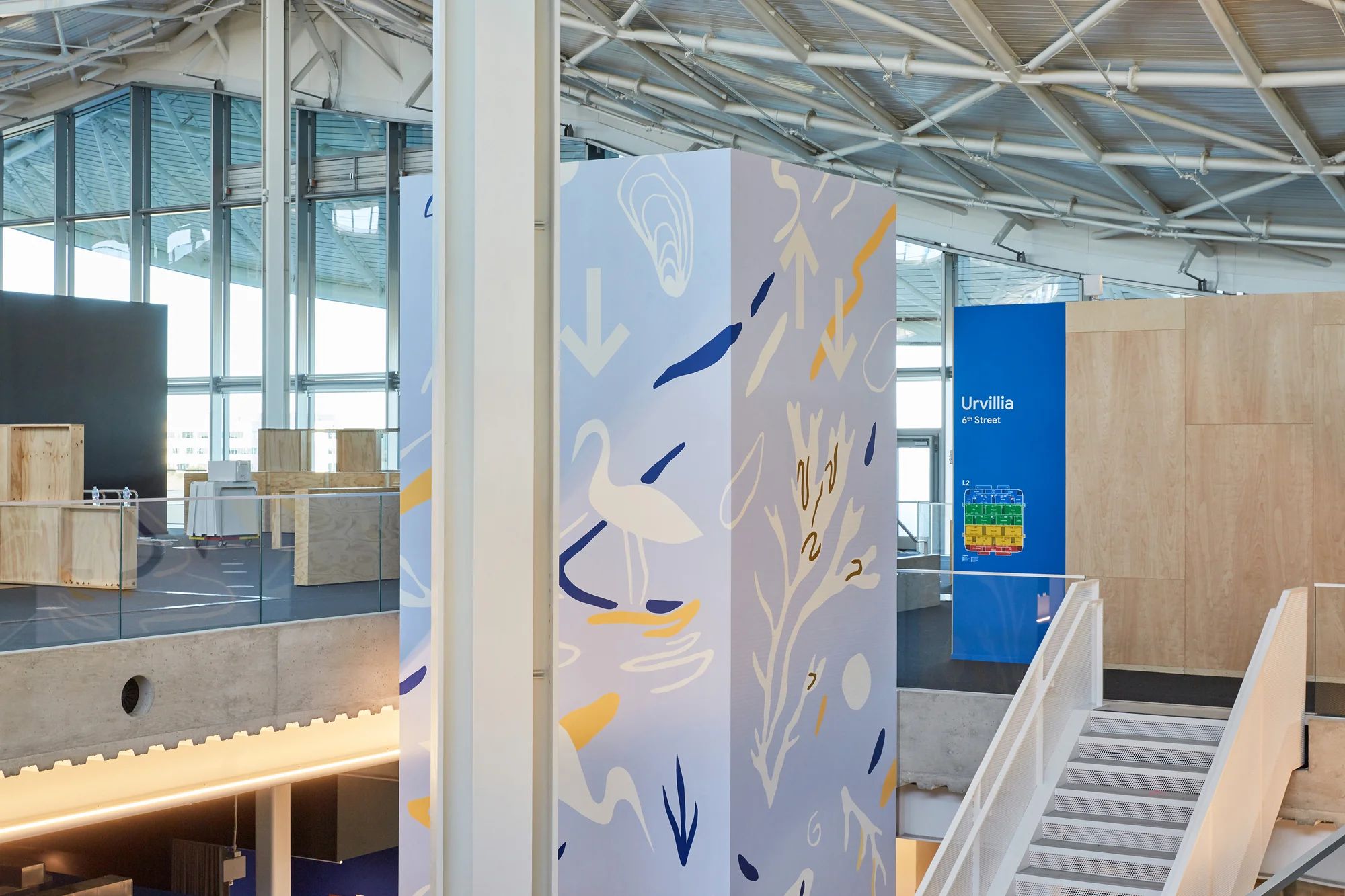 A photograph of Tess's mural on an elevator. The mural has a blue background with illustrations of birds and grasses against it.