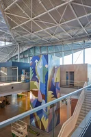 A photograph of Rachel's mural on an elevator. Various abstract shapes primarily in blue and green shades suggest water and grasses.