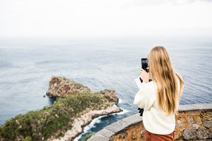 woman taking a photo of a coastal view