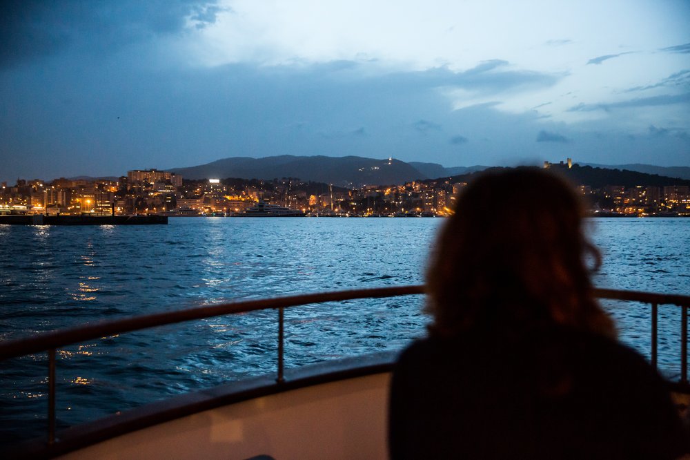 someone sitting on a boat at sunset watching the shoreline