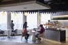 Googlers conversam em torno de mesas circulares em um café de escritório em frente a janelas do chão ao teto com vista para a Torre de Tóquio.