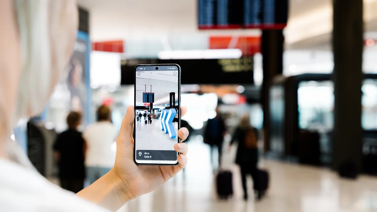 A photo of a person holding up a smartphone at the Airport, showing the AR navigation features