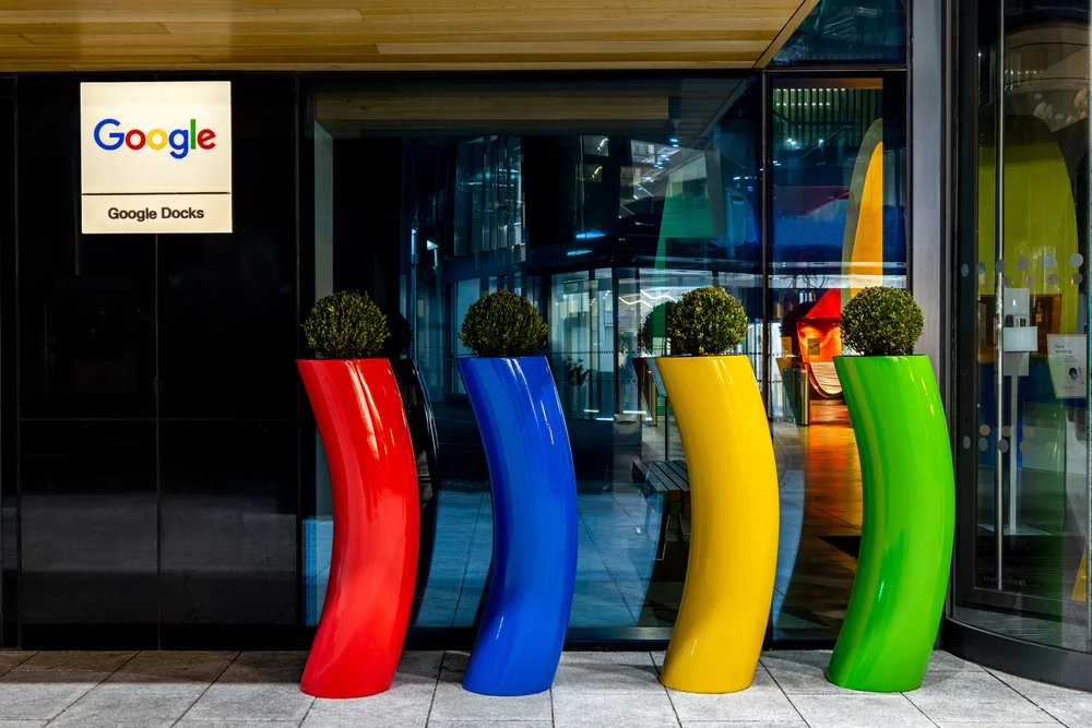 View of the front entrance of the Google Docks office building in Dublin, with four curved, colorful, metal pillars in red, blue, yellow and green in front of it.