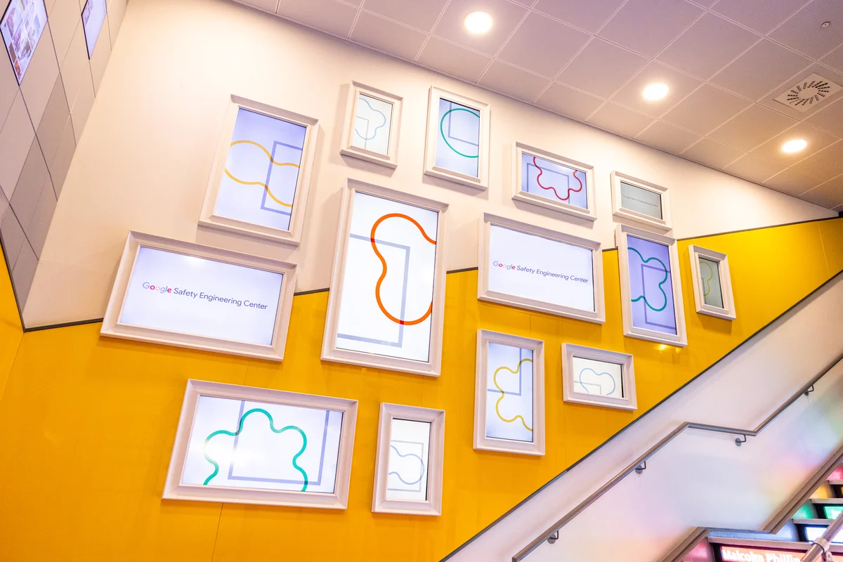 Photo of Google Safety Engineering Center interior staircase with thick yellow lines along the walls and large, white picture frames. The stairs are lit in blue, green, yellow and red lights.