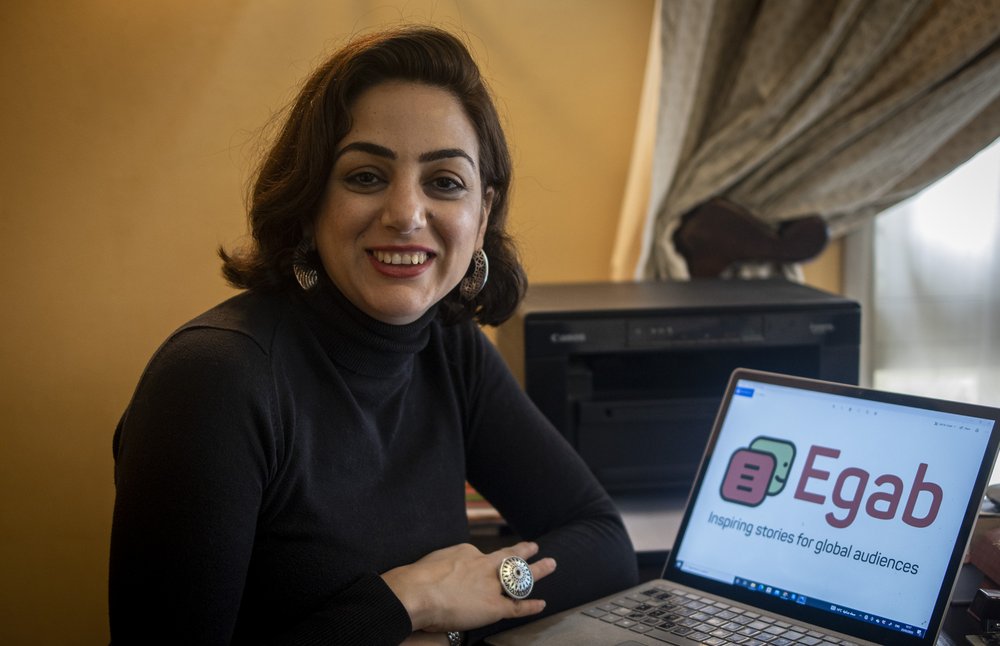 Picture shows Egab founder Dina Aboughazala sitting on a sofa with her laptop in front of her