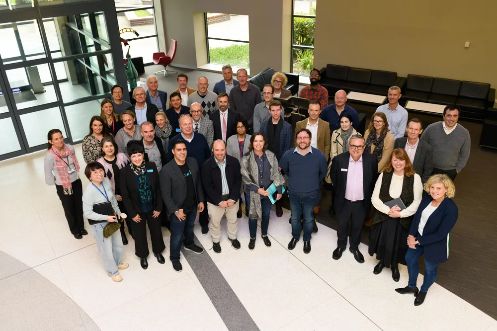 
                         
                           All partners standing together in a group, attending a workshop at Macquarie University
                         
                       
