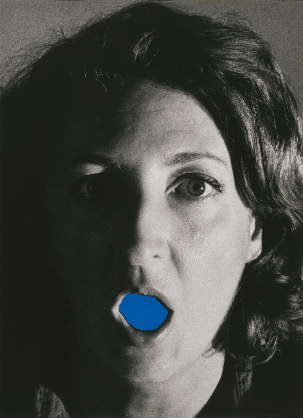 A work of art by Helena Almeida, featuring a black-and-white portrait of a woman with her mouth open. The inside of the mouth is painted blue.