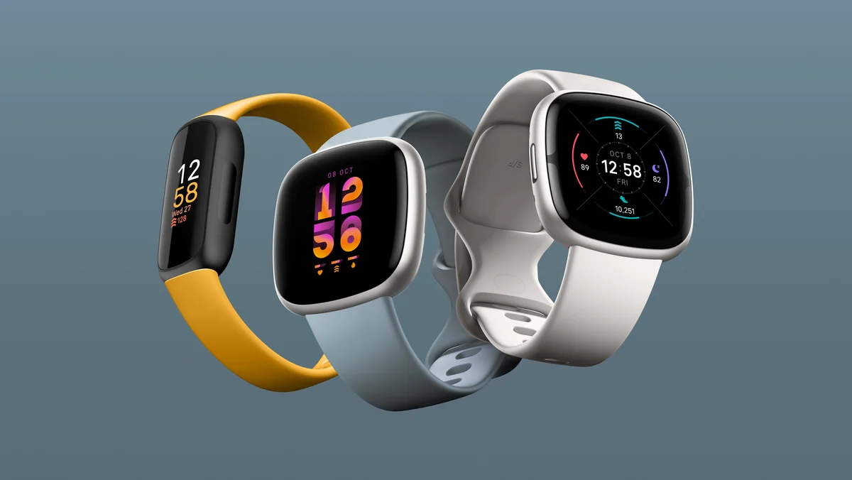 A photo of the new Fitbit devices, showcasing Inspire 3 in morning glow, Versa 4 in waterfall blue and Sense 2 in lunar white, each side-by-side, showing a different colourful clock face.