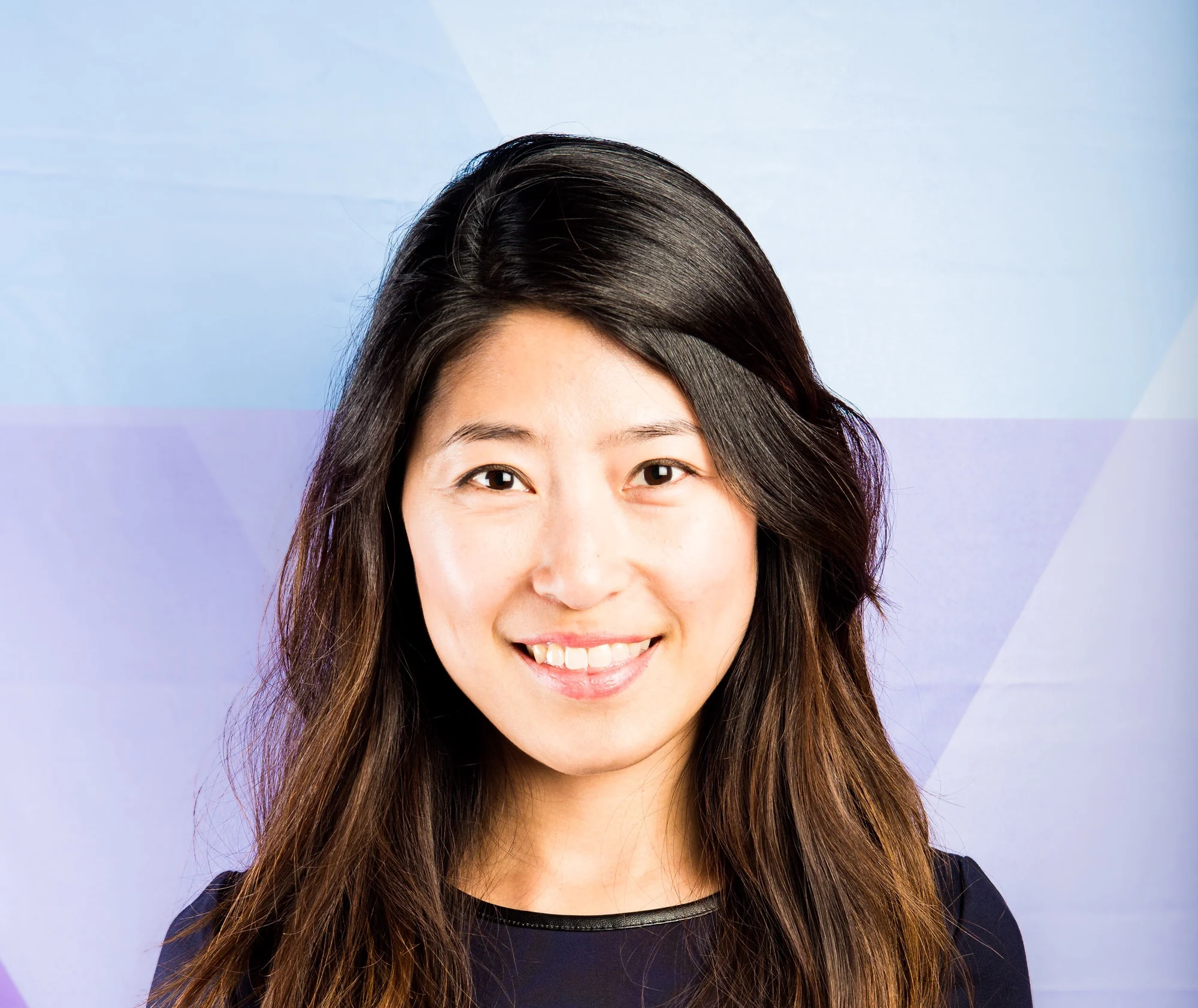 A headshot of a person with long dark hair against a purple and blue background