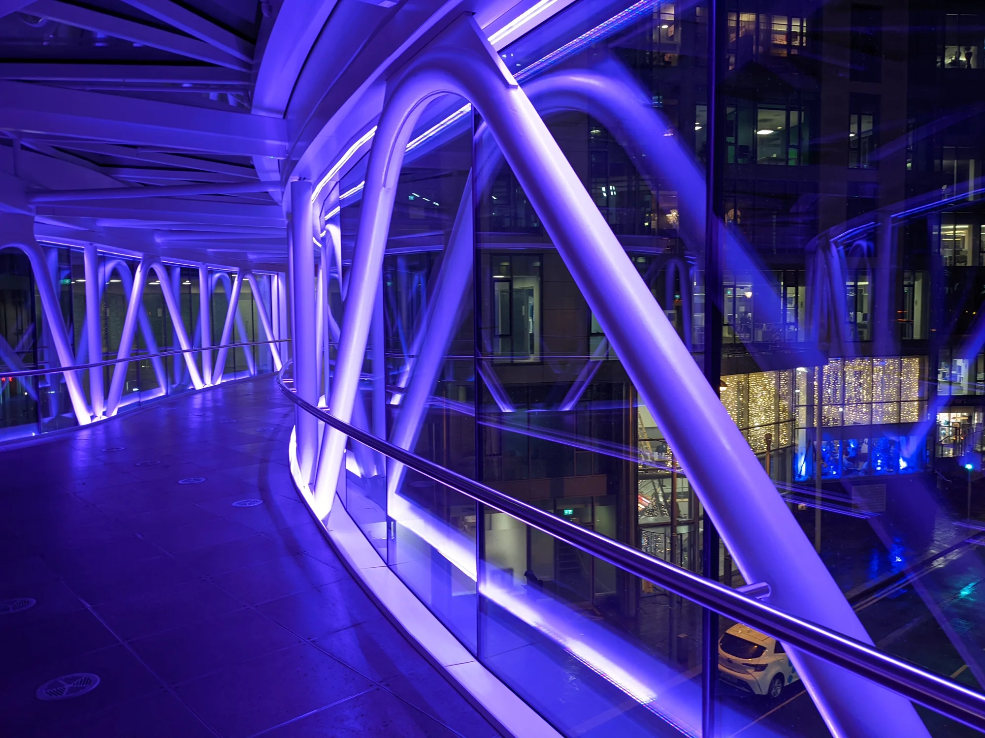 Bild, aufgenommen in der sogenannten Hyperlink-Brücke, die drei Google-Büros in Dublin miteinander verbindet. Die Brücke ist lila erleuchtet, was auch von außen zu sehen ist.