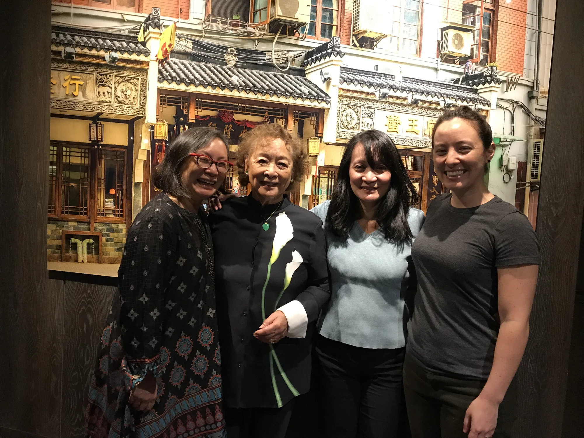 A photograph of four women standing together and smiling at the camera.