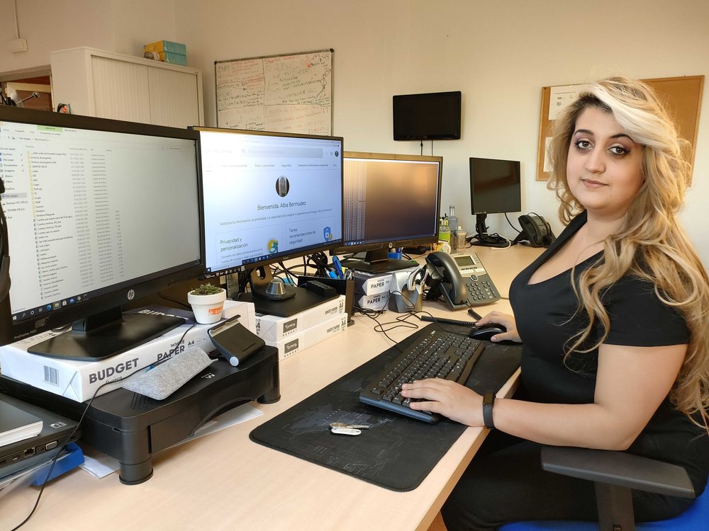 A picture of Alba Bermúdez at her desk facing her computer