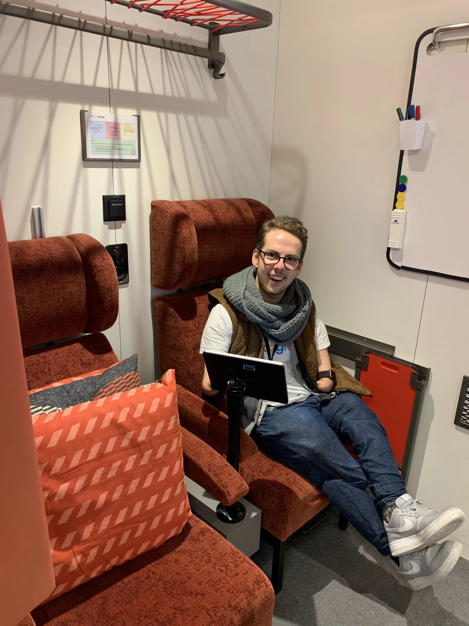 Patrick Schilling sitzt auf einem Zugabteil nachempfunden Konferenzraum im Züricher Google-Büro und lächelt in die Kamera.