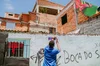 A man hangs a Plus Codes sign on the wall of a house in Favela dos Sonhos.