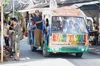 a colorful bus on a crowded road filled with people labeled “Ban Tawai” and “free service”