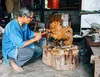 a person squatting on the floor and carving an animal sculpture out of wood.