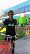 Satyaki on a bike in front of an Android statue. He is wearing a Code Jam shirt.