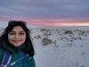 Divya smiling in front of a sunset.
