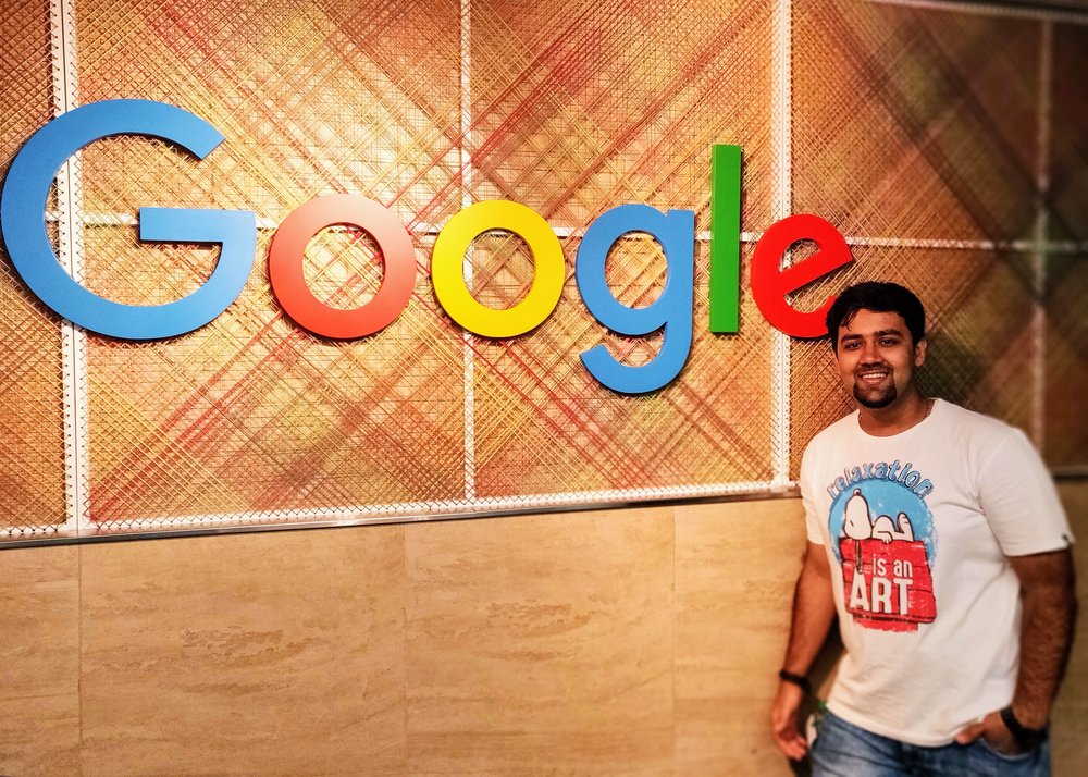 Nikhil standing indoors in front of a Google sign.