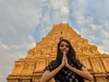 Snehal holding her hands together outdoors in front of a large structure.