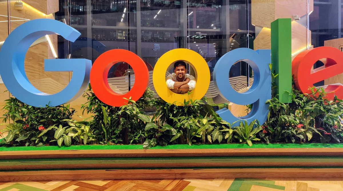 Nikhil standing indoors behind a large Google sign.