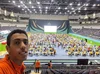 Yosri at the International Olympiad of Informatics 2019 in Baku, Azerbaijan. Yosri looks over an arena where participants in yellow and orange shirts sit at tables and work at laptops.