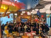 A group photo of male and female Google employees at the office cafe smiling and dressed up in party gear, celebrating Google’s global 21st anniversary.